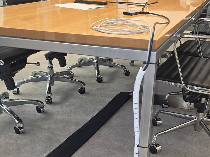 Meeting room boardroom table with cabling dressed into a spiral wrap and a floor cord cover across the carpet